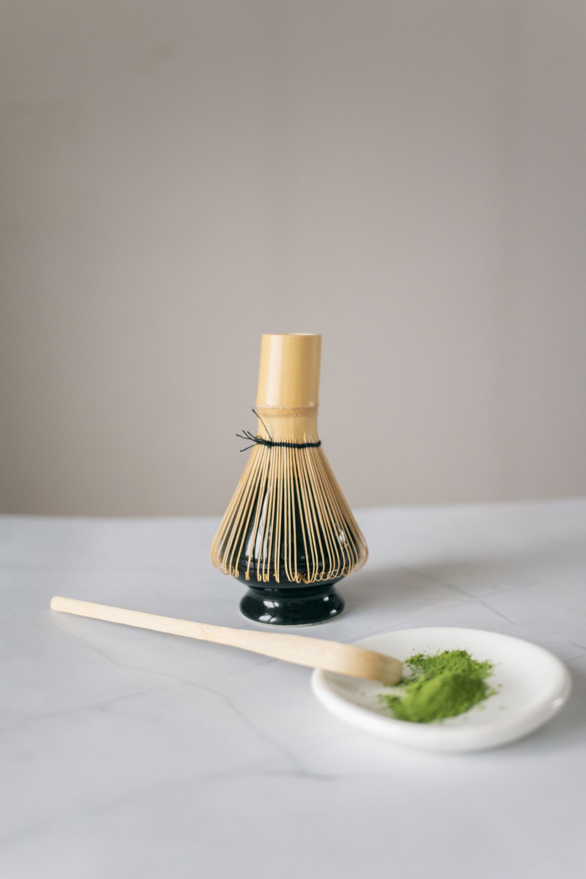 A bamboo whisk and a scoop of green powder